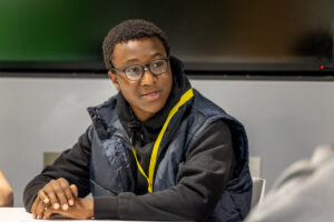 A young person in a yellow lanyard engaged in a discussion.