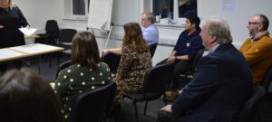 A group of Youth Scotland employees sit in a conference room, listening to a presentation.