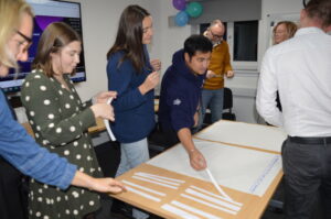 A group of Youth Scotland staff members stand around a table, completing an activity with poster pages.