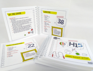 A stack of wire-bound Hi5 Games Toolkits are arranged, showing colourful interior pages with lots of graphics.