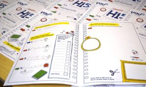 The interior pages of a Youth Scotland Hi5 Award are arranged in a stack.
