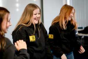 Three young girls smile while wearing a Reach hoodie