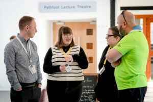 A group of youth workers share a conversation in the lobby of Stirling University