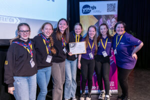 A group of young people smile and pose with a Youth Scotland award certificate.