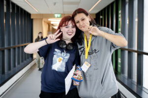 Two young people smile and give the peace sign.