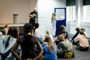 A youth group have a discussion in a circle while someone draws on a flipchart