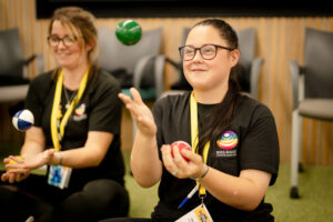A group learn how to juggle small, coloured balls in a circus skills workshop