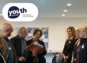 Adults have a conversation while standing. Youth Scotland logo.